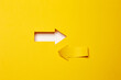 Two opposite left/right arrows, one cutted from the yellow paper curved up of two sides on the yellow paper background other made as an arrow shaped hole in the background with white paper underlay