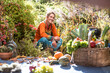 © Hans Huber/Westend61 - Smiling woman harvesting fruit and vegetable while sitting in garden