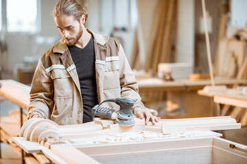 Wall Mural - Handsome carpenter checks out carving quality of a joiner's product at the carpentry manufacturing