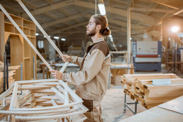 Wall Mural - Handsome carpenter checking the quality of the window frame before the paint at the carpentry workshop