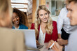 © peter scholl/Westend61 - Smiling woman looking at colleague while sitting in meeting at office