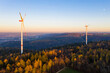 © Werner Dieterich/Westend61 - Wind turbines standing in autumn forest at dusk