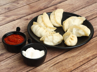 Wall Mural - Paneer steam momo. Nepalese Traditional dish Momo stuffed with paneer and then cooked and served with sauce and mayonnaise over a rustic wooden background, selective focus