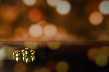 Golden wedding rings on sparkle bokeh background. Selective focus with copy space for text. Wedding card and invitation background. Champagne color. 