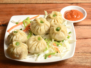 Wall Mural - Veg steam momo. Nepalese Traditional dish Momo stuffed with vegetables and then cooked and served with sauce over a rustic wooden background, selective focus