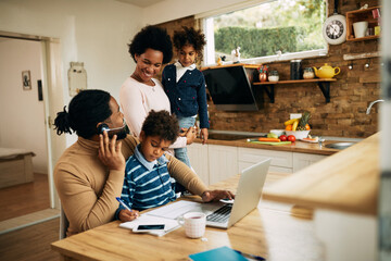 Wall Mural - Happy African American woman talking to her husband who is working at home.