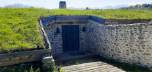 House Or Bunker Built Of Stone Underground With Solid Wood Door And Natural Grass Roof
