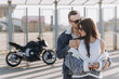 © Liubomir - Sexy girl and guy hugging and kissing on the background of a sports motorcycle standing in the parking lot near a large football stadium