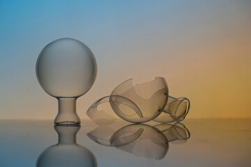 Closeup shot of a crystal ball and broken glass pieces on a glass surface