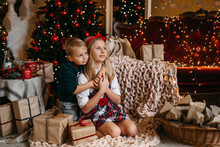  Little Boy And Girl Are Sitting Near The Christmas Tree And Hugging. Happy Brother And Sister