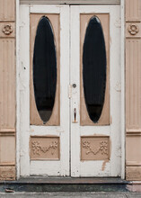 Close Up Color Photo Of Old Front Doors On A Closed Storefront With Thick Layers Of Peeling Paint And Ornate Carvings.