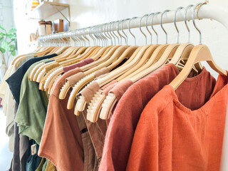 Long rack with women's clothing arranged in rainbow order hanging from wooden hangers