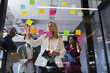 © Wavebreak Media - Diverse business people brainstorming by glass board in office
