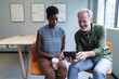 © Wavebreak Media - Diverse man and woman drinking coffee using digital tablet in creative office
