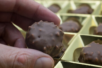 Wall Mural - Closeup of chocolate in hand  on golden box presentation background