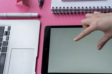 Sticker - Hand on a tablet with markers, notebook, laptop, swan origami, and smartphone on pink background