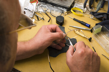 Wall Mural - Concept of optical workshop.Expert fixing eyeglasses.Closeup of human hads, glasses, screwdrivers and other professional tools for repairing.Optical workshop