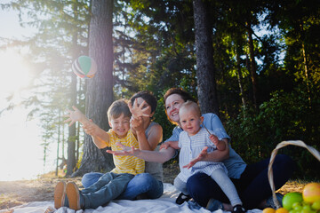 Homosexual lesbian family with two children, a son and a daughter. Two moms and kids at an outdoor picnic. Forest and sea.