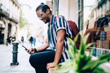 Cheerful man surfing internet on smartphone on city street