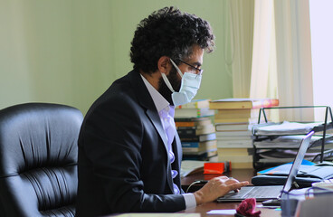 Businessman wearing face mask and working in the office during virus epidemic.