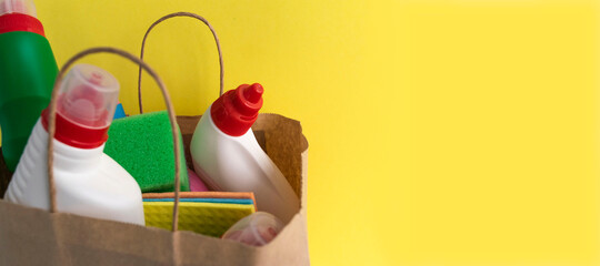 House cleaning supplies on yellow background. Row of plastic bottles with cleaning liquid and sponges. Cleaning business, production, shopping and delivery donation. copy space