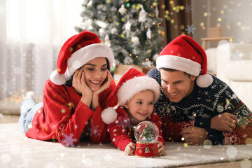 Poster - Family in Santa hats playing with snow globe at home