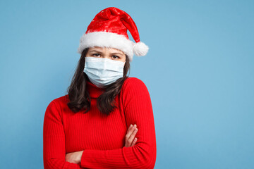 portrait of a anxious woman in a Christmas cap and protective medical mask.