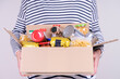 © vejaa - Volunteer hands holding food donations box with grocery products on white desk