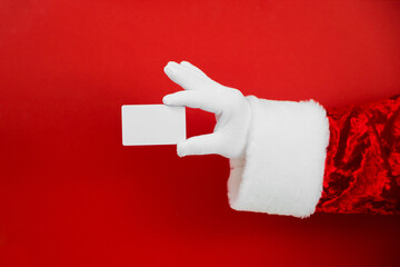 Santa Claus hand holding blank plastic credit card on red background with Clipping Path. Shopping, Sales, Giving Gift for Black Friday, Christmas and New Year concepts