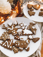 Wall Mural - Christmas gingerbread cookies on white plate on rustic wooden table with lights