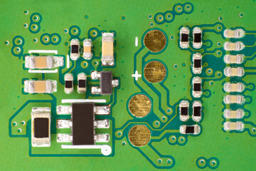 Green electronic circuit, with gold electrical contacts and various electrical components connected together.