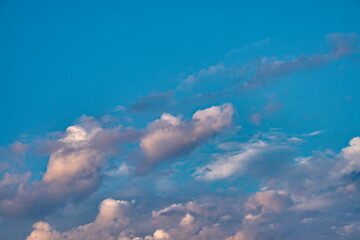 bands of shaded clouds of gray and orange floating under a sky in blue heaven.