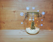 View of a jar filled with white capsules and a Christmas tree with lights and Christmas ornaments on wooden background with copy space. Medical or pharmacology background.