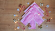 Christmas tree made of pink surgical masks with colorful Christmas ornaments, decorations and lights on a warm wooden background. Safe Christmas or medical background. 