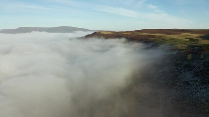 Wall Mural - Aerial view of a narrow, winding road on a hillside surrounded by fog and cloud