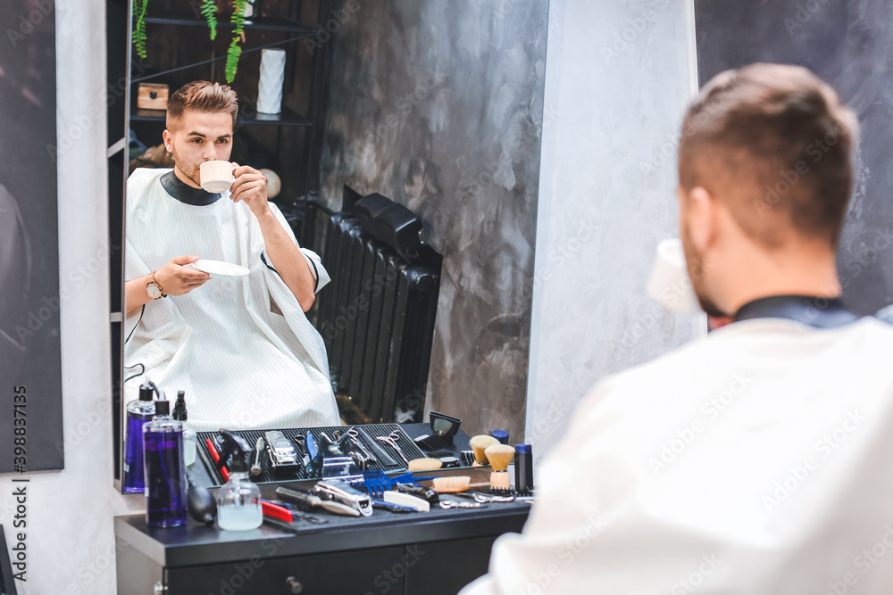 Handsome man drinking coffee in barbershop