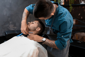 Wall Mural - Hairdresser shaving client in barbershop