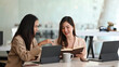 © Prathankarnpap - Two businesswomen employees colleagues using computer tablet and discussing working together on business project.