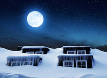 Window With Icicles And Snow Cover On The Roof In The Night Sky With Moon. Winter Season.