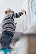 © astrosystem - Handyman worker making hole for airduct ventilation in the kitchen.