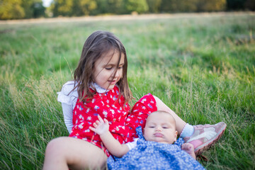 Adorable little girl and baby lying down on the grass