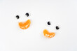 Smiling figures with orange mandarin slice mouths. Happiness, nutrition, vitamin, funny concept. Top view, flat lay, copy space