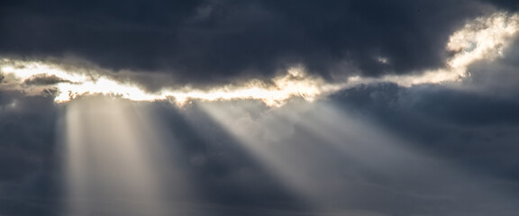 Wall Mural - Sunrays breaking through dark clouds