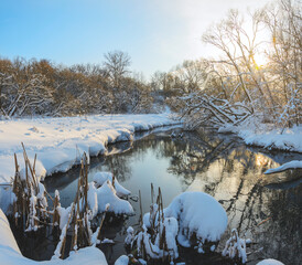 Wall Mural - Frosty winter scene with forest river during sunny january morning. Beautiful snow covered trees in the glow of rising sun. 