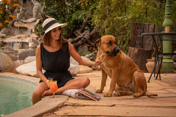 Poster - Brunette in hat strokes dog by pool