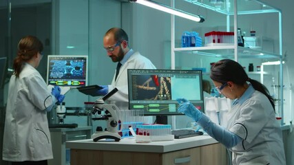 Wall Mural - Scientist team checking virus development using high tech writing analysis results on computer in modern equipped lab at night. Doctors examining vaccine evolution with special tools for research.