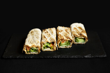 Wall Mural - Pita dish with grilled meat and vegetables on black background