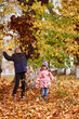 © Екатерина Мазур - A boy of 7 years and a girl of 4 years play leaves autumn. Brother and sister autumn park all yellow fun game