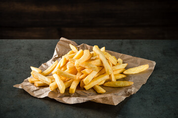 Wall Mural - Potatoes fries on kraft paper on table, French fries close up