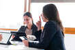 © SebastianCava - business meeting 4 people with laptops ipad tablet folios pens and folios in bright office with large windows three women and a man happy smiling